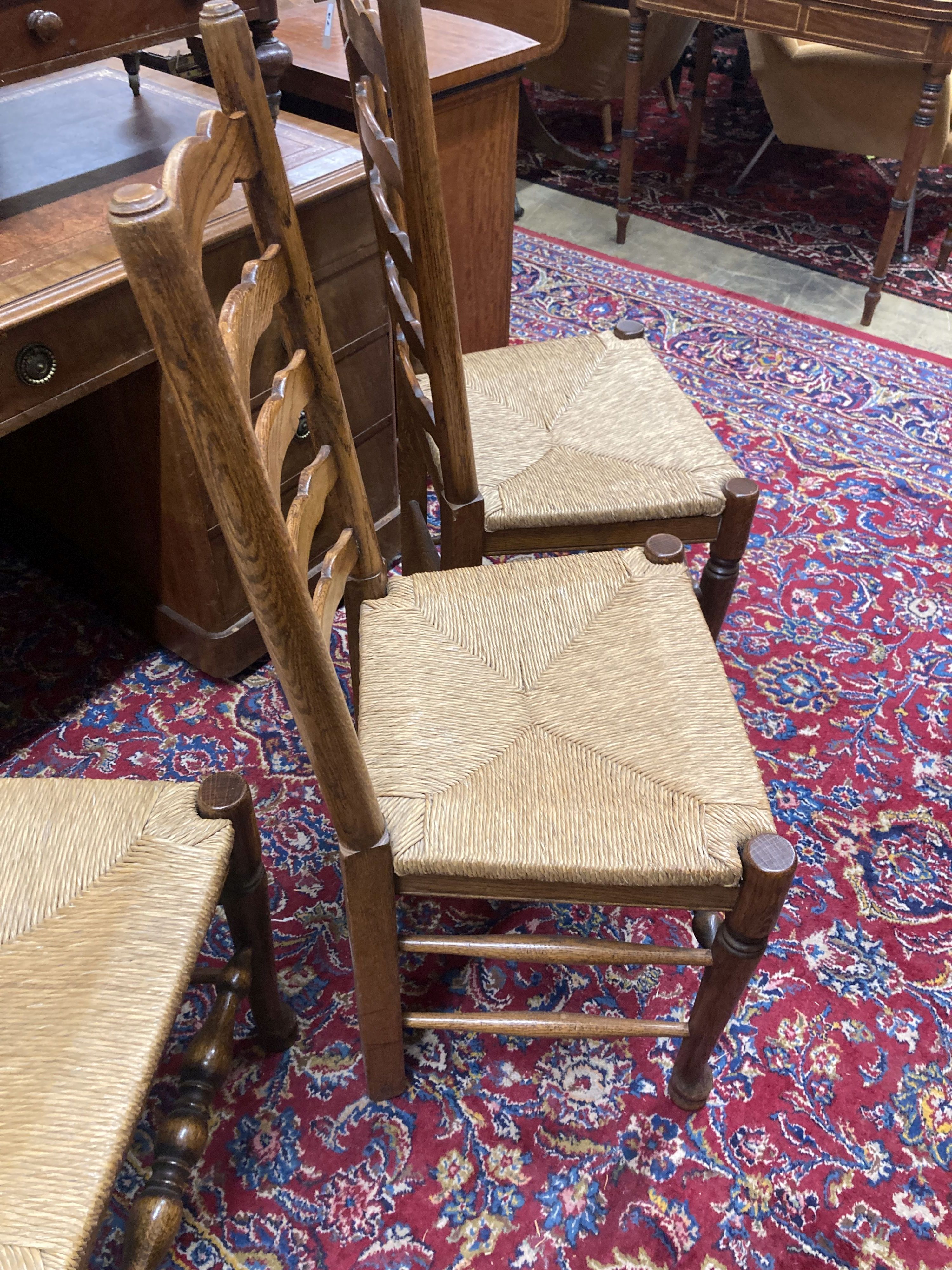 A set of eight 18th century style oak rush seat ladderback dining chairs, (two with arms)